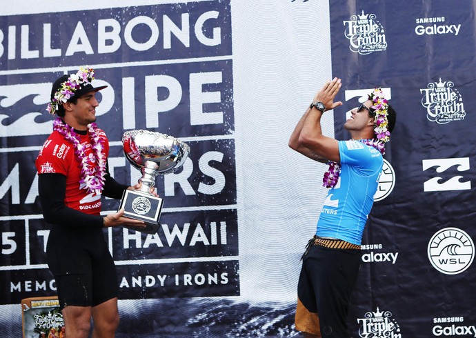 Gabriel Medina entrega o troféu de campeão mundial para as mãos de Mineirinho (Crédito: David Abramvezt)