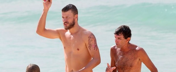 Rodrigo Hilbert exibe a barriga tanquinho em dia de praia com filho