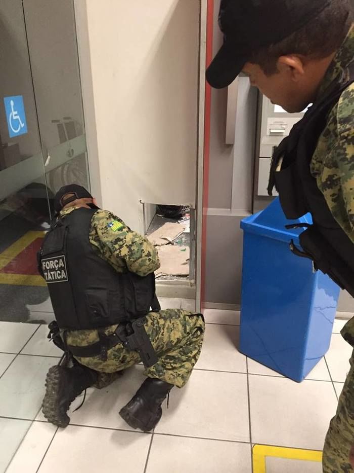 Policiais observam o buraco feito pelos bandidos (Crédito: Reprodução)