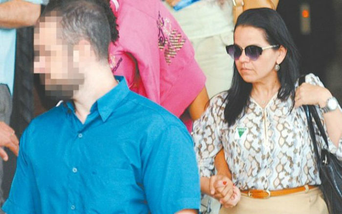 Jovem de 16 anos (com o rosto coberto) deixa delegacia após prestar depoimento sobre caso