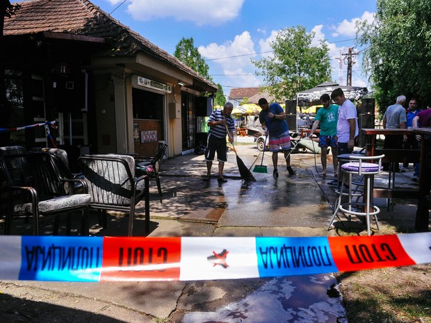 Pessoas lavam a calçada de um café onde um homem matou cinco pessoas em Zitiste, na Sérvia, neste sábado (2) (Crédito: AFP)