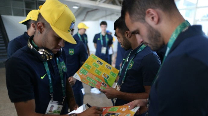 Neymar e Renato Augusto com o álbum da Olimpíada (Crédito: Divulgação/ CBF)