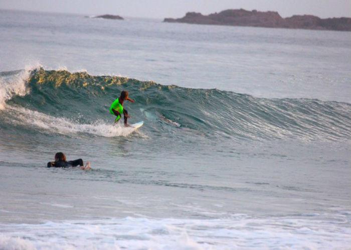 Pai flagra tubarão ao lado do filho ao fotografar criança surfando (Crédito: Chris Hasson via AP) )