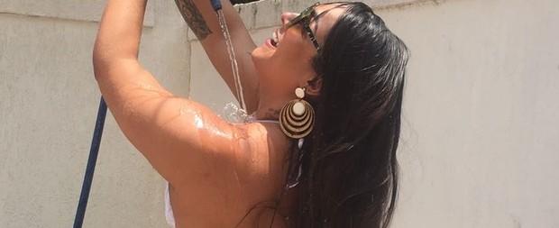 Mulher Melancia se refresca com magueira no quintal de casa; fotos