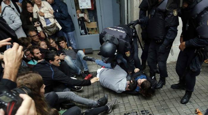 Policiais espanhóis imobilizam duas pessoas do lado de fora de um local de votação em Barcelona, no dia de um referendo que vota a independência da Catalunha (Crédito: Pau Barrena/AFP)