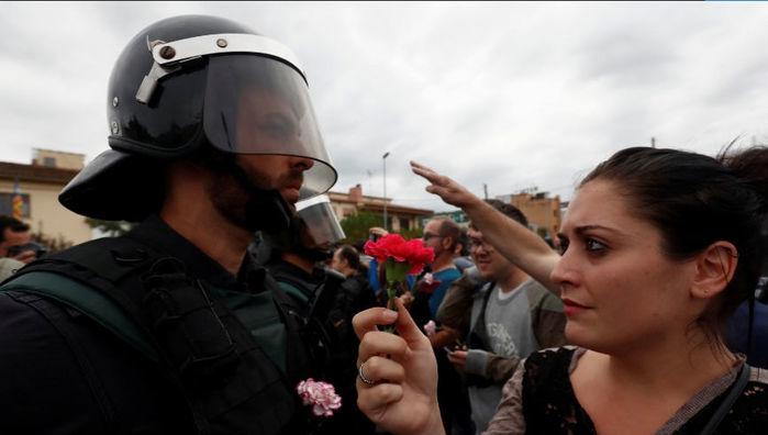 Mulher oferece flor a oficial da Guarda Civil Espanhola após o bloqueio do centro de votação em Sant Julia de Ramis (Crédito: Juan Medina/Reuters)