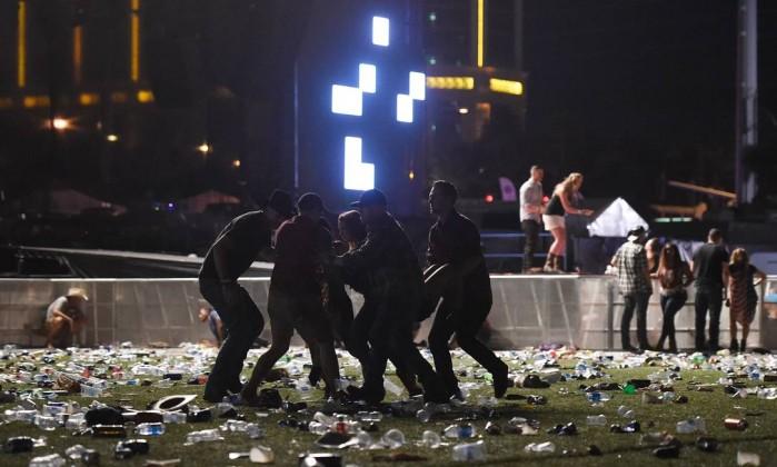 Pessoas ajudam ferido após tiros em Las Vegas (Crédito: AFP)