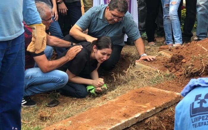 Mãe e pai (à direita) de João Vitor choram ao enterrar o corpo do filho (Crédito: TV Anhanguera )
