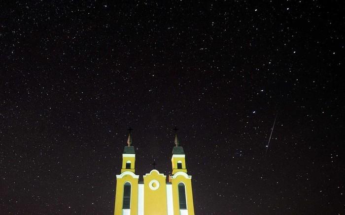 Meteoro no o céu atrás de uma igreja católica na vila de Krevo, a cerca de 100 km a noroeste de Minsk, na Biolorrússia (Crédito: Sergei Gapon / AFP Photo)