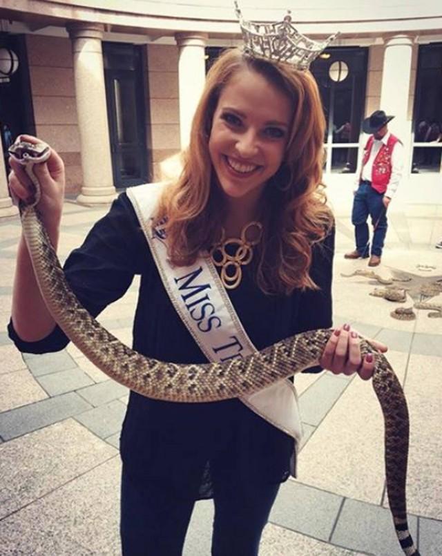 Miss posa sorridente ao segurar cobra cascavel