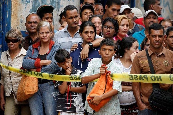 Moradores observam trabalho de investigadores em frente à padaria saqueada em Caracas (Crédito: Reprodução)