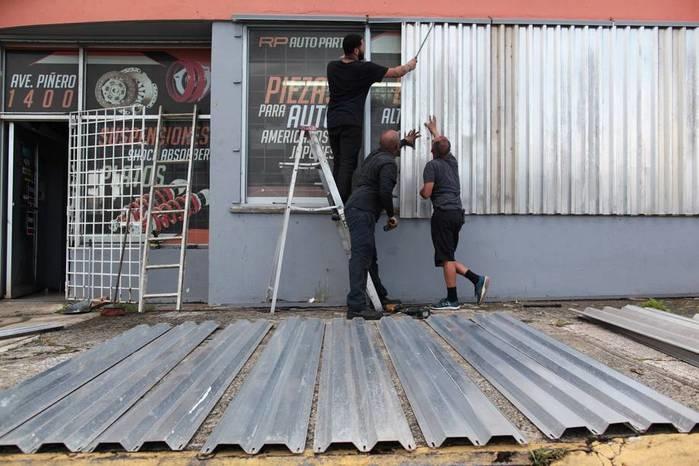 Homens protegem janelas com placas para a chegada do Furacão Irma, (Crédito: Reuters)