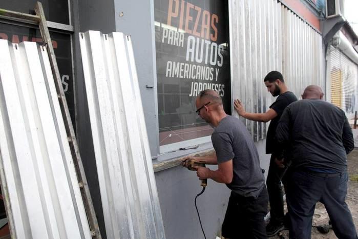 Homens protegem janelas com placas  (Crédito: Reuters)