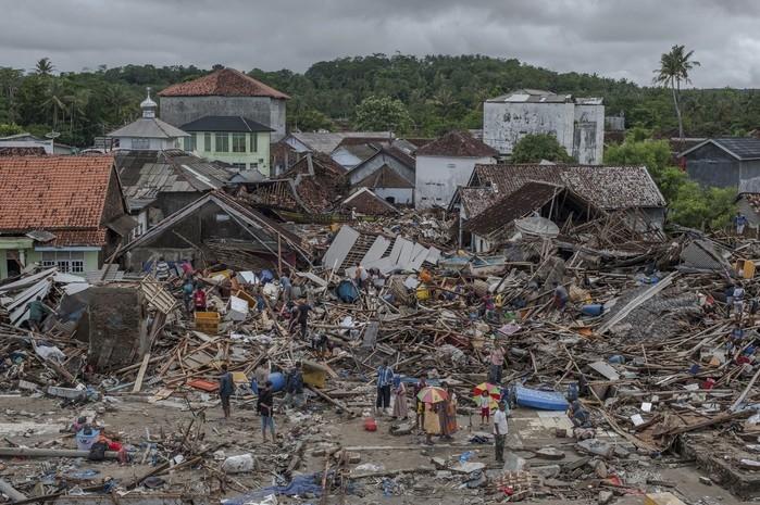 Pessoas inspecionam nesta segunda-feira (24) área destruída pelo tsunami em Sumur, na Indonésia (Crédito: Fauzy Chaniago/AP Photo )
