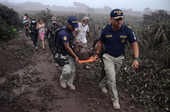 Policiais carregam ferido na erupção do Vulcão do Fogo, em El Rodeo, no departamento de Escuintla, no domingo (3) (Crédito: Noe Perez / AFP)