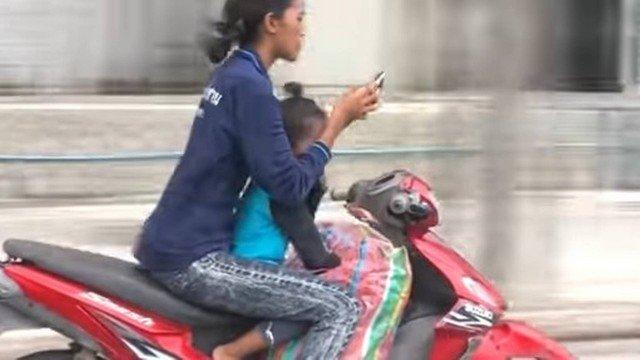 Mulher tira as mãos do guidão ao usar smartphone sobre moto (Crédito: Reprodução/YouTube)