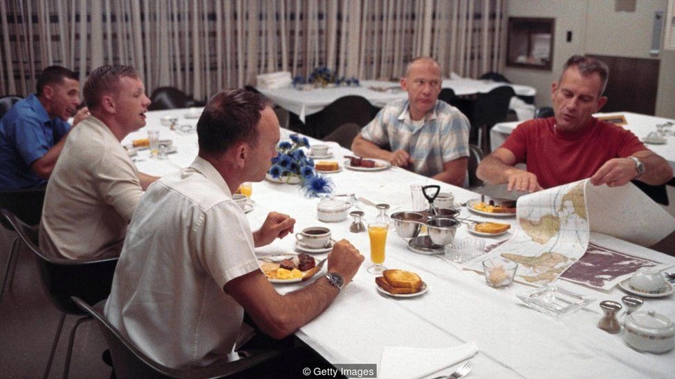 Tripulação da Apollo 11 sentada à mesa, antes de lançamento