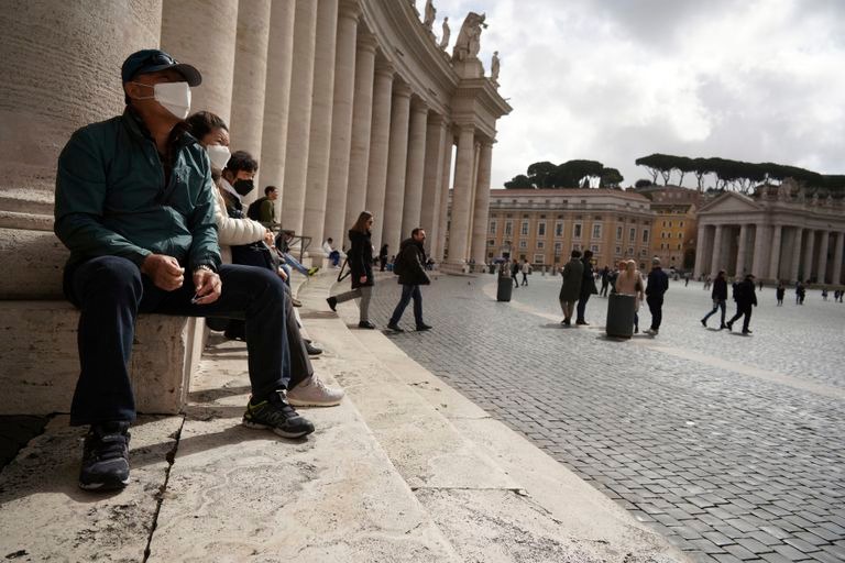 People sit by Bernini"s colonnade in St. Peter"s Square at the Vatican, Friday, March 6, 2020. A Vatican spokesman has confirmed the first case of coronavirus at the city-state. Vatican spokesman Matteo Bruni said Friday that non-emergency medical services at the Vatican have been closed so they can be sanitized following the positive test on Thursday. (AP Photo/Andrew Medichini)